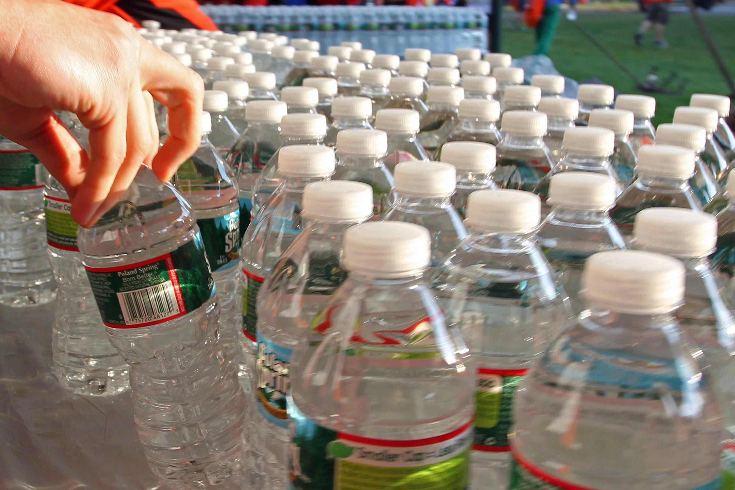 A runner grabs a bottle of water at the athlete's village prior to the start of the 116th running of the Boston Marathon, in Hopkinton