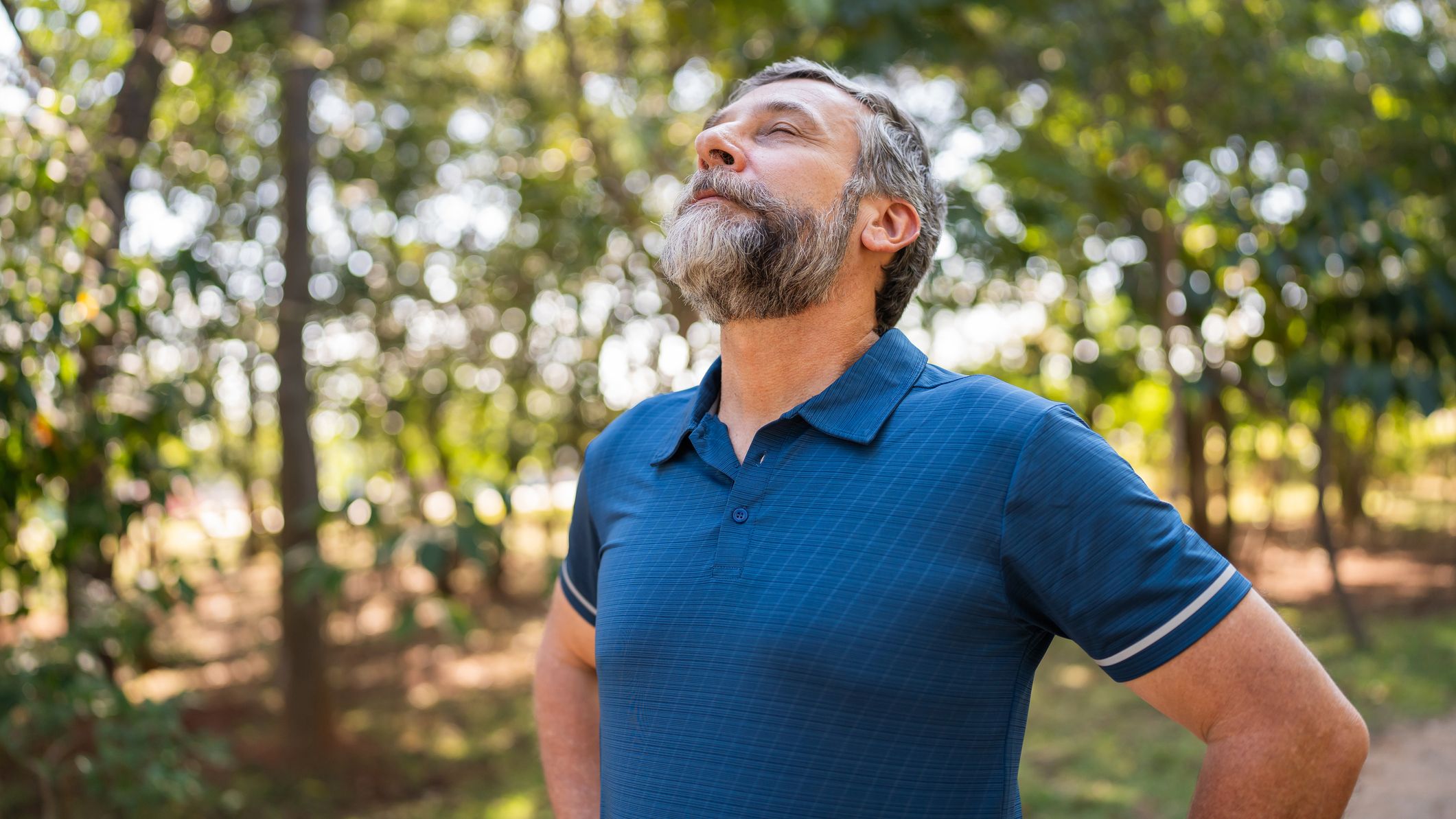 A man stands outside with his head tilted back and eyes closed