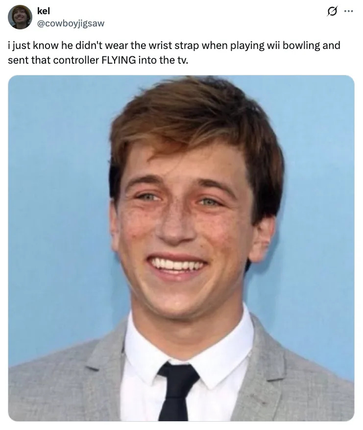Skyler Gisondo in a suit smiling widely against a plain backdrop, tweet text reads, "i just know he didn't wear the wrist strap when playing wii bowling and sent that controller flying into the TV"