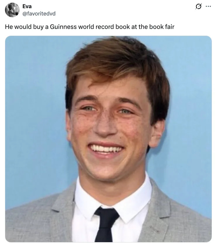 Skyler Gisondo smiling in a suit jacket and shirt, with freckles visible. Text above mentions buying a Guinness World Record book at a bookfair