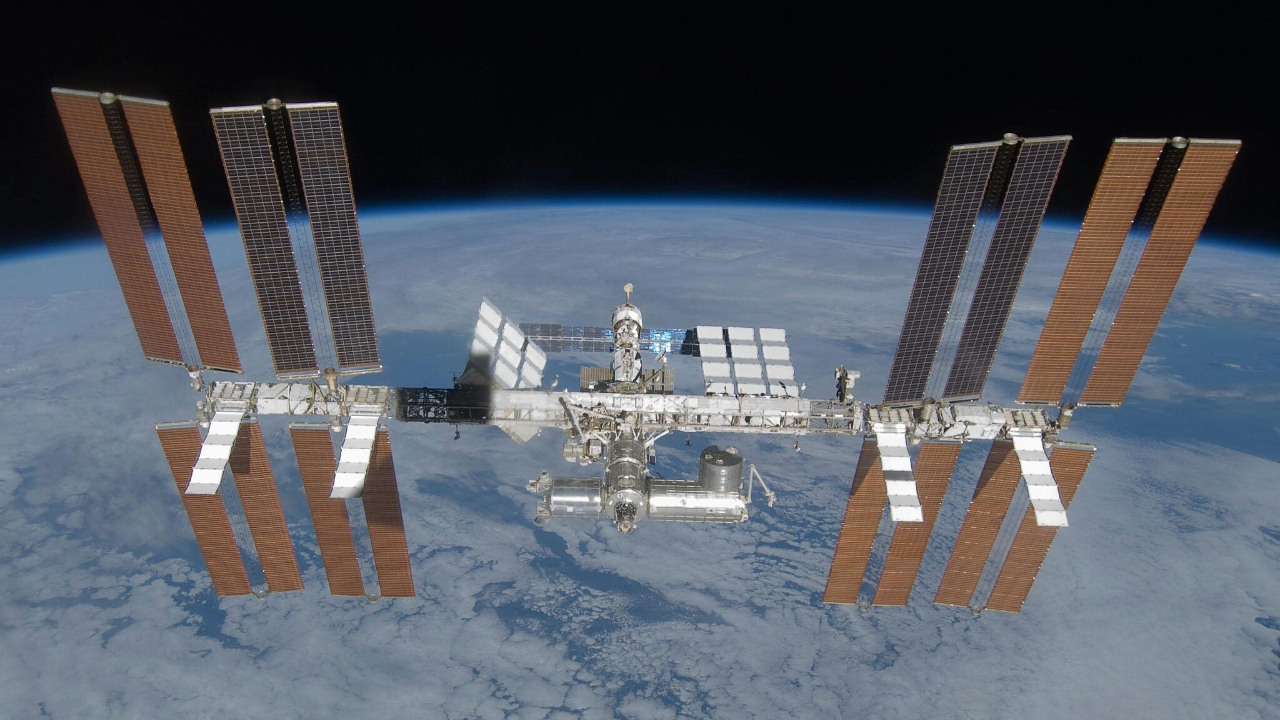 An image of the International Space Station, with its many solar panels and modules, floating above Earth in space