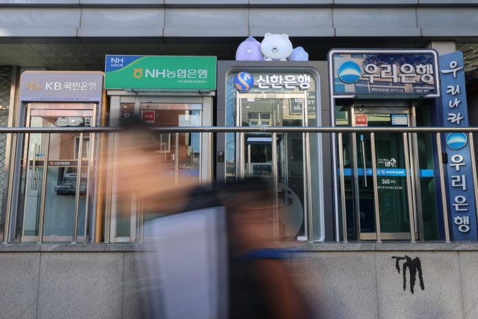 Bank data breach victims step up calls for compensation Pedestrians walk past a row of ATMs from Korea