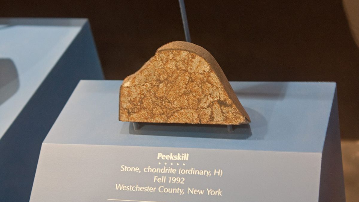 On this day in space! Oct. 9, 1992: Peekskill meteorite an orange and brown-striped chunk of rock with a smooth, rounded top edge and a flat cross-section face