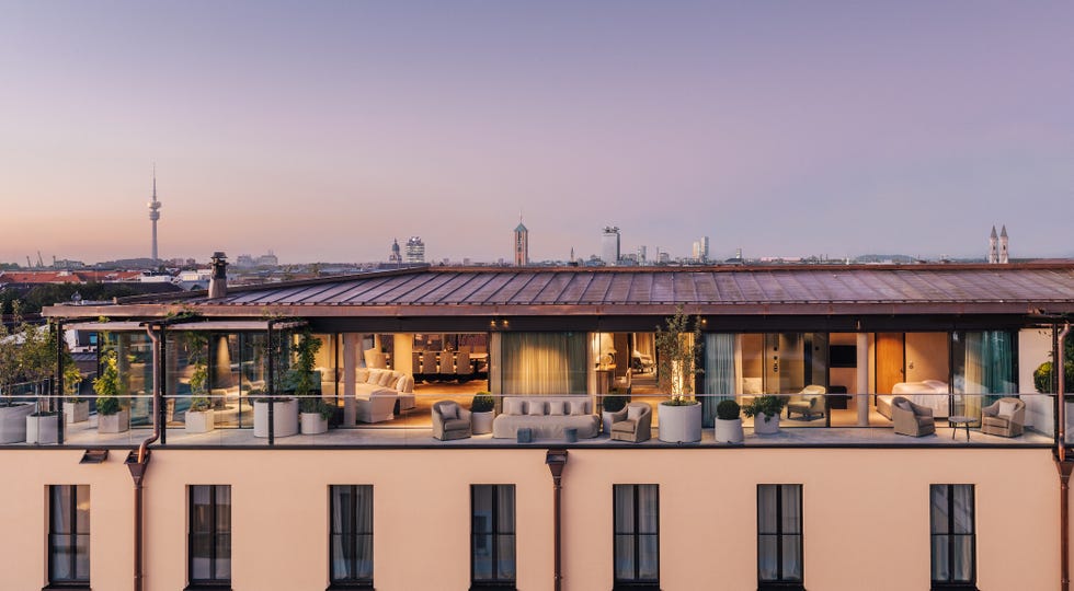 Rooftop lounge overlooking a city skyline at dusk with modern furniture and greenery.