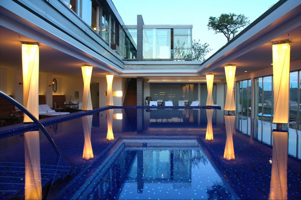 Modern indoor pool area with stylish lighting and reflections, showcasing a serene ambiance.