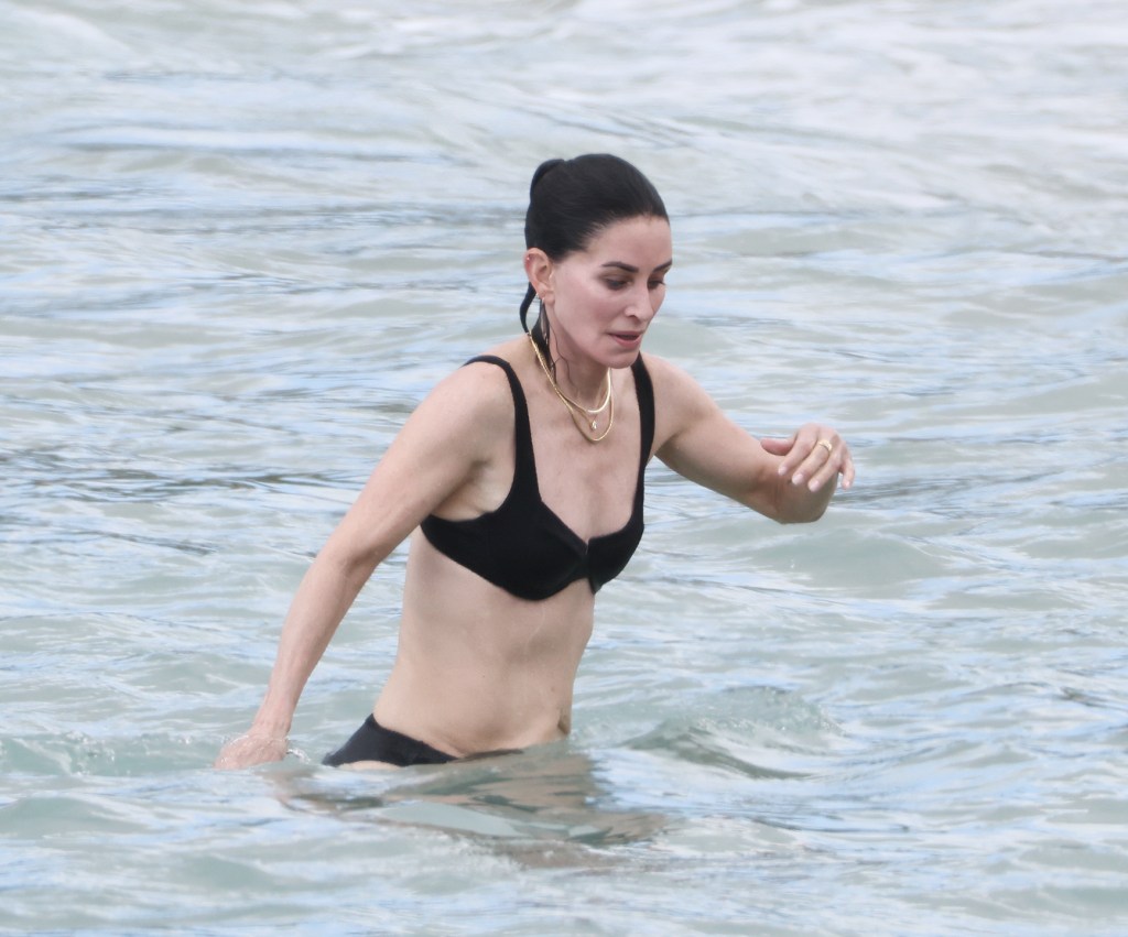 Courteney Cox wearing a black bikini in the ocean in Hawaii.