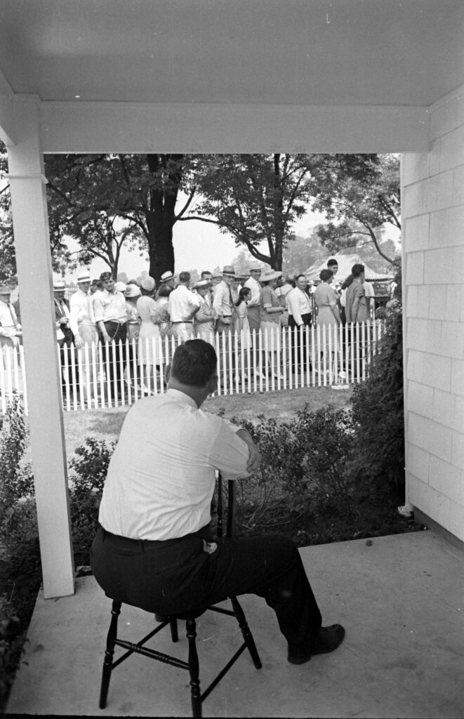 Frank Engels looked out at the people waiting in line to observe his family, named "Ohio's most typical farm family," at the Ohio state fair, 1941.
