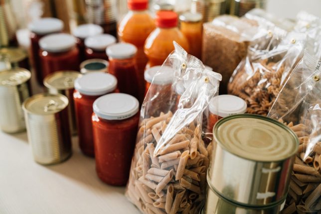 Rearranging the kitchen pantry. Many cans, bottles and tins on the kitchen table. Panic buying concept.