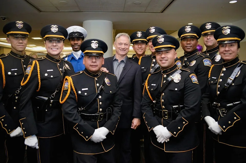 A group photo of several uniformed officers and a person in civilian attire standing together indoors