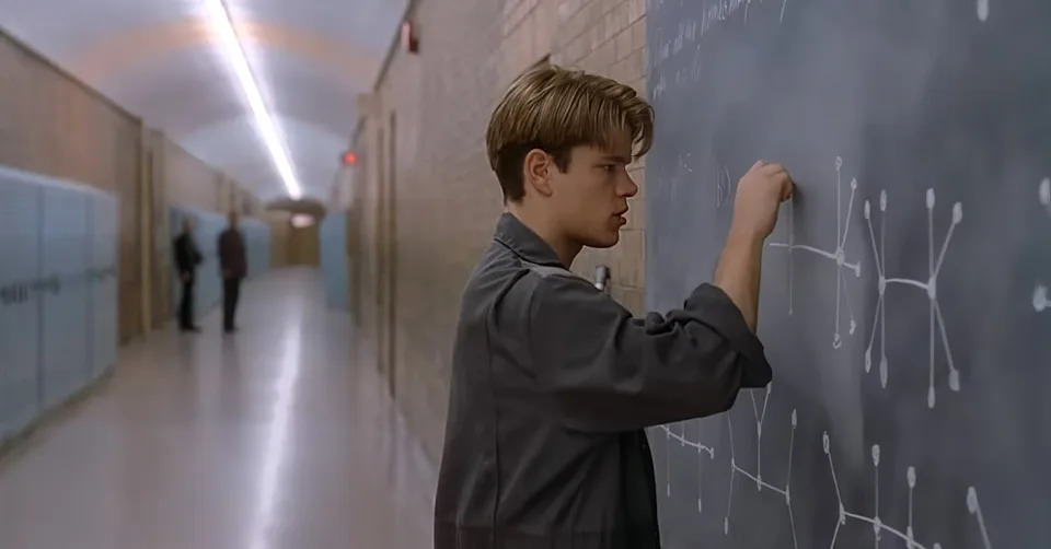Person writing complex equations on a chalkboard in a quiet hallway, appearing focused and unaware of the surroundings