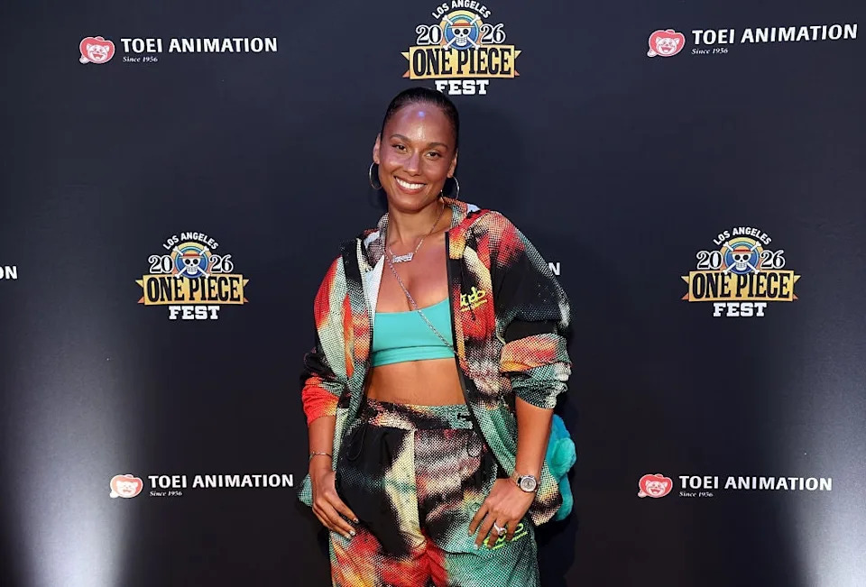 Person in a stylish, colorful tracksuit poses on the red carpet at the One Piece Fest, smiling confidently