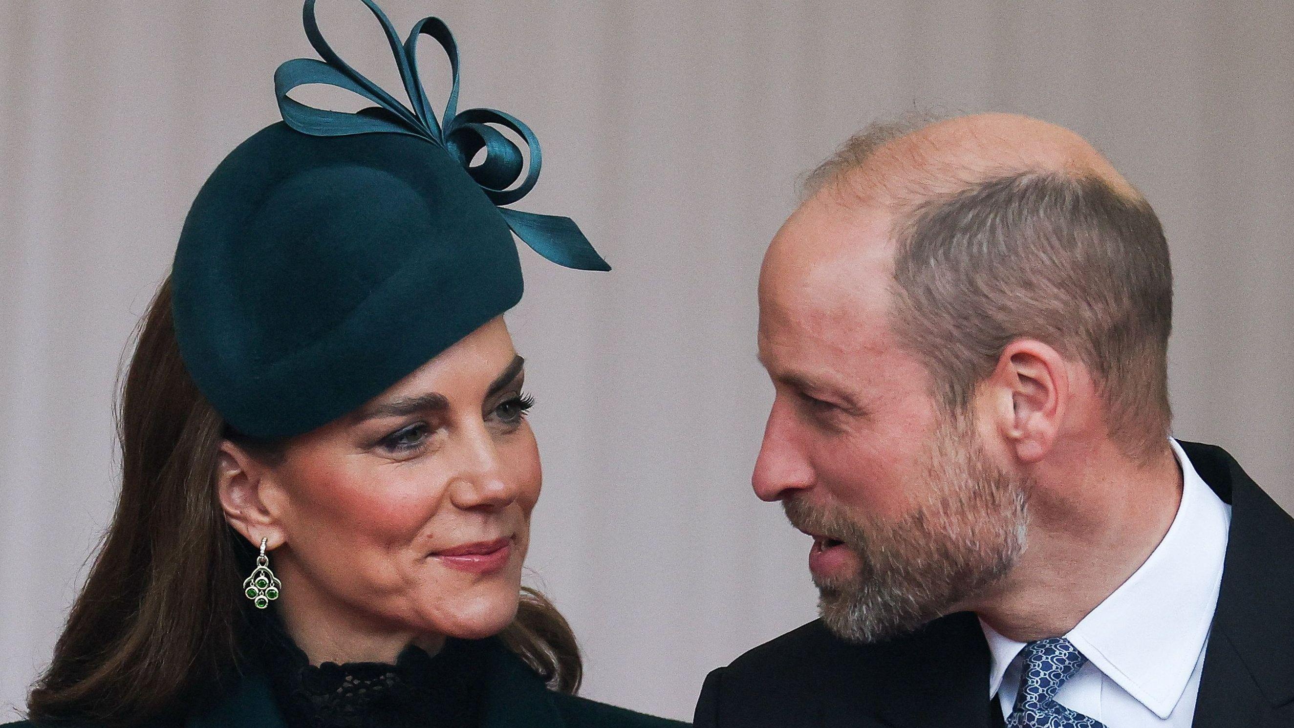 The Prince and Princess of Wales turned to each other in conversation - the prince wears a suit and the princess wears a dark green hat and large earrings, with her hair down