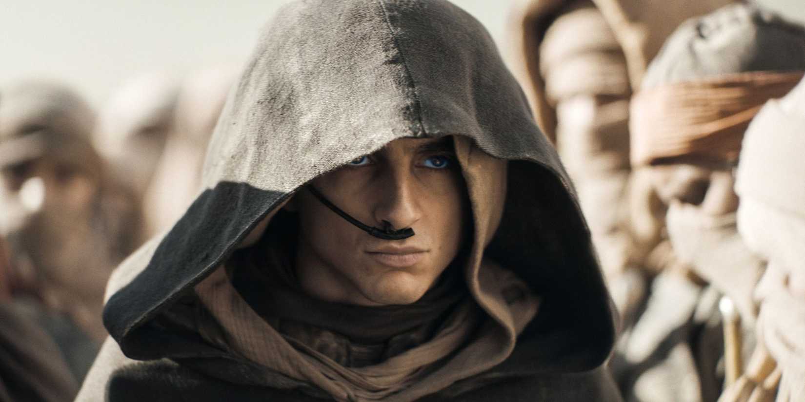 Hooded Paul surrounded by followers in Dune Part 2.