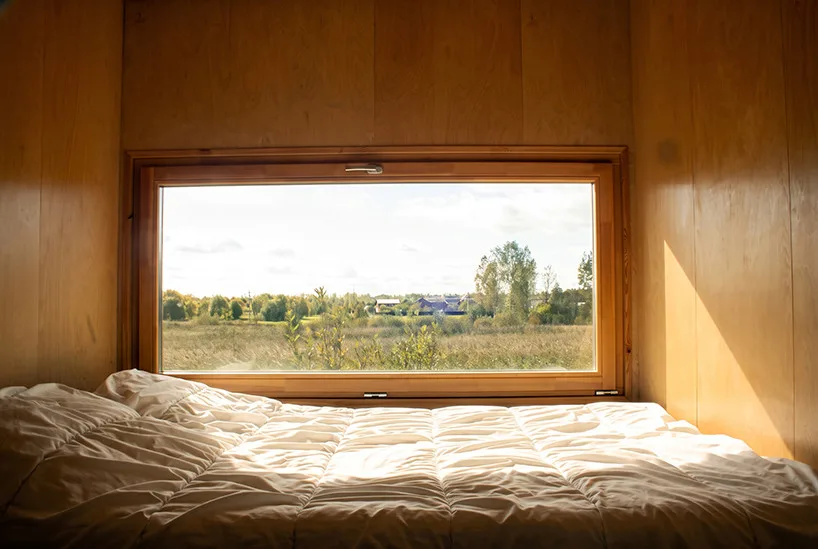 Innovative Birch Plywood Interior Transforms Shipping Container into Modern Micro-Cabin Large windows in living area offer views of surrounding landscape.