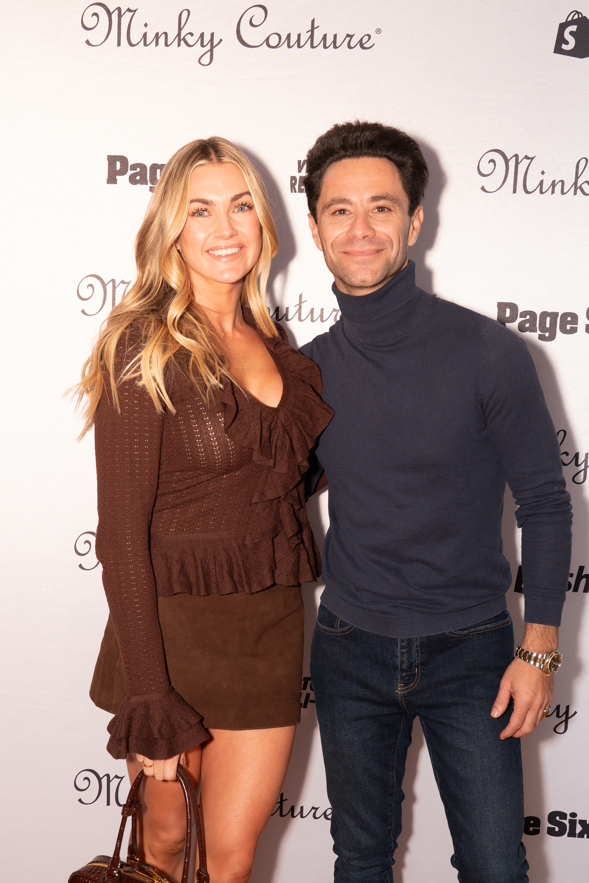 Britt Stewart and her husband, Daniel Narvaez, pose in front of a step-and-repeat backdrop.