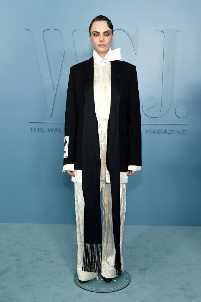 Cara Delevingne poses in a black blazer and white satin shirt and pants at the WSJ. Magazine Innovator Awards.