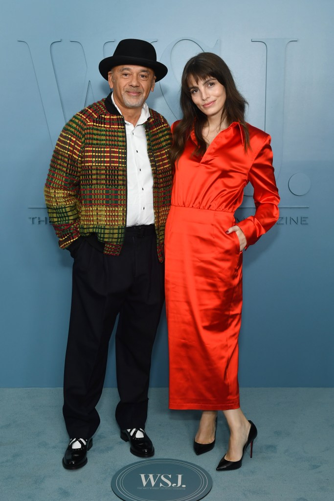 Christian Louboutin and Lux Pascal attend an event together, posing in front of a blue backdrop.