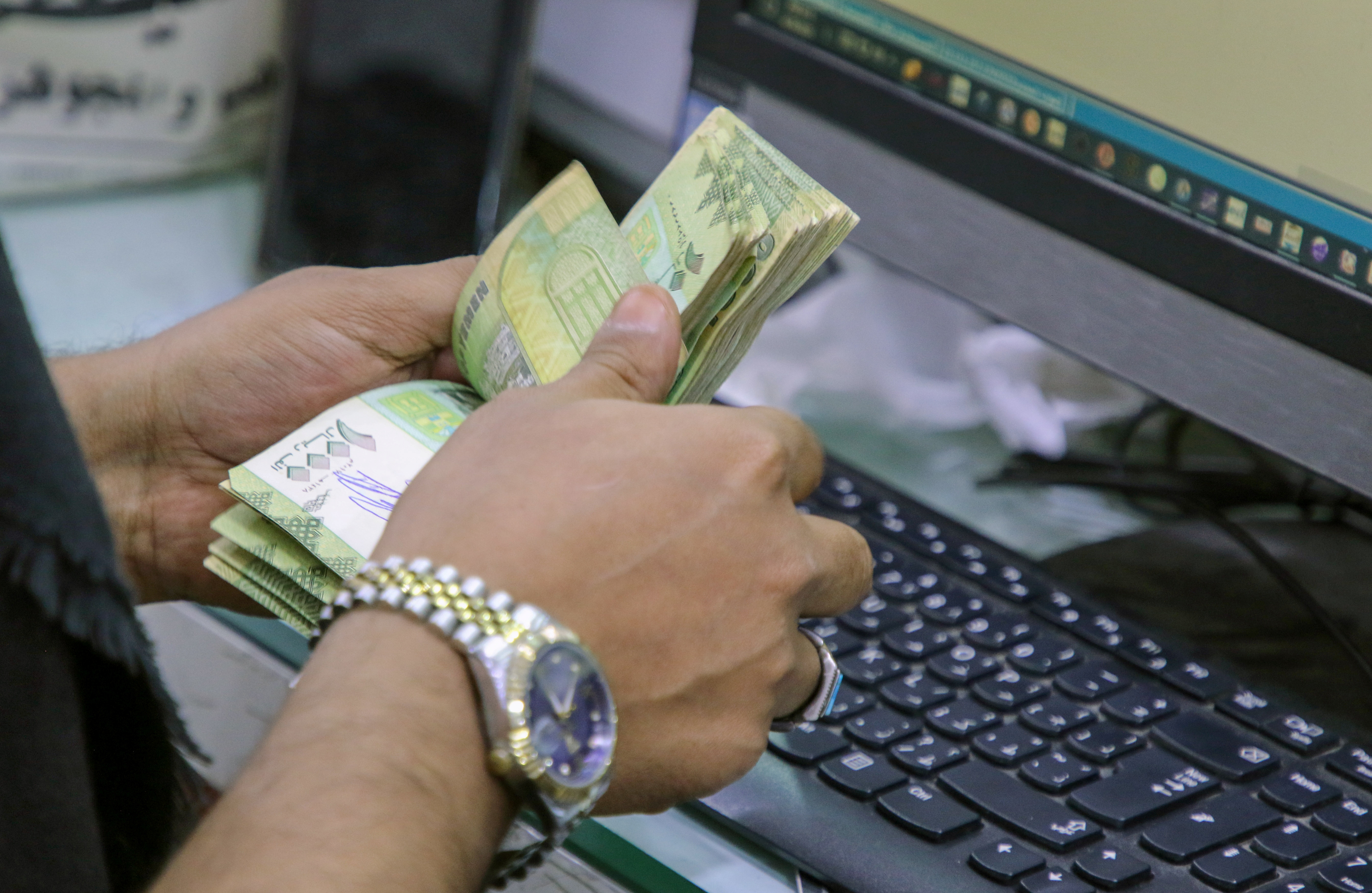 A cashier counts Yemeni riyal banknotes at a local currency exchange in Aden, Yemen, June 29, 2021. (Reuters file)