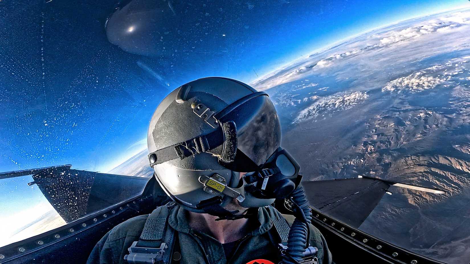 A photo of Louis Skupien in the backseat of the F-16 looking out over a mountain range.