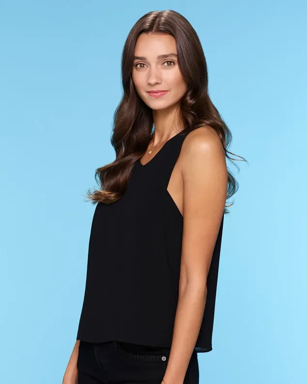 Woman with long hair in black top against blue background. Woman with long hair in black top against blue background.